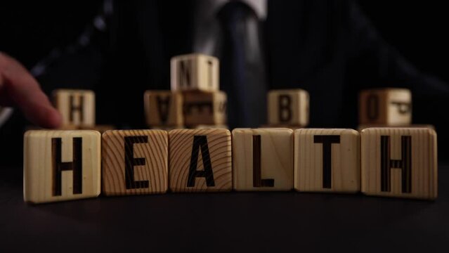 Hand flip wooden cube with word wealth to health.