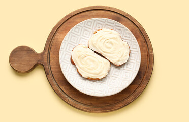 Wooden board of tasty sandwiches with cream cheese on yellow background