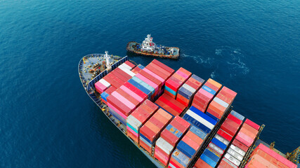 Aerial top view of cargo ship carrying container and running with tug boat for import export goods from cargo yard port to custom ocean concept freight shipping by ship .