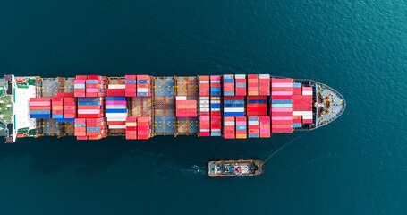 Aerial top view of cargo ship carrying container and running with tug boat for import export goods...