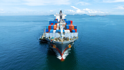 Aerial front view of cargo ship carrying container and running with tug boat for import export...