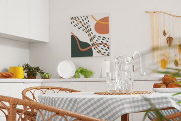 Dining table with jug of water and glasses in modern kitchen