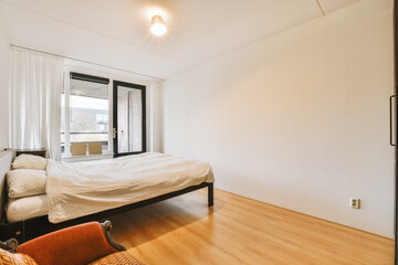 a bedroom with wood floors and white walls, including a bed in the corner of the room has a sliding glass door that leads