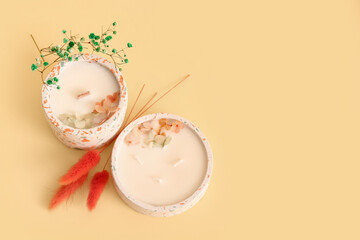 Holders with candles and flowers on beige background