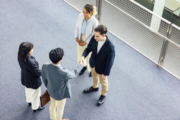 Multinational business group shaking hands in lobby. Global business. High angle view. - obrazy, fototapety, plakaty