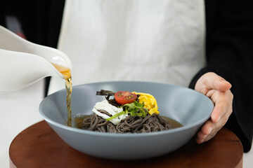chef holding bowl of noodles