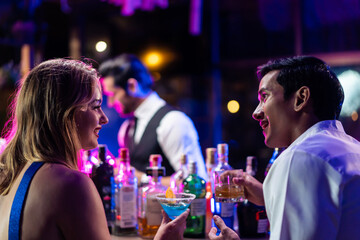 Beautiful young couple having fun, drinking alcohol cocktail in a bar. 
