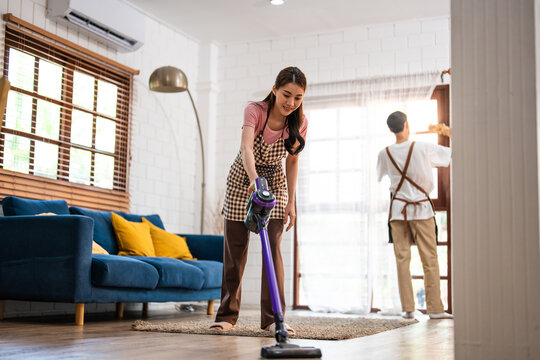 Asian attractive young man and woman cleaning house indoors together. 