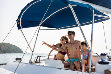 Caucasian happy family driving yacht outdoors on the sea during summer.