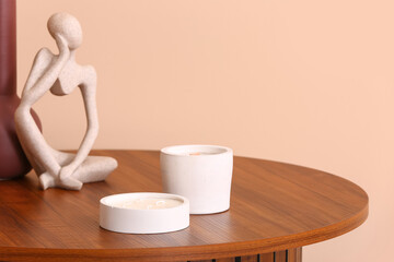 Holders with candles and decor on table near beige wall in room