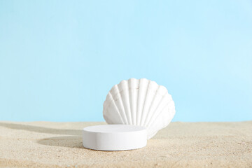 Decorative plaster podium with seashell on sand against blue background