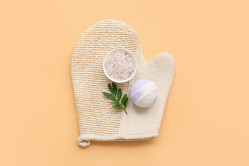 Massage glove, sea salt and bath bomb on color background