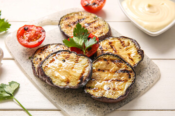 Delicious grilled eggplants, sauce and tomatoes on white wooden background