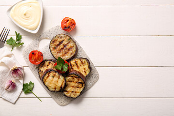 Delicious grilled eggplants, sauce and tomatoes on white wooden background