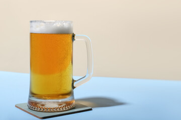 Mug of cold beer on color background, closeup