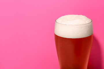 Glass of cold beer on pink background, closeup