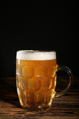 Mug of cold beer on wooden table
