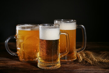 Mugs of cold beer and spikelets on wooden table