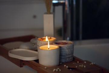 Holders with burning candles on wooden stand in bathroom, closeup