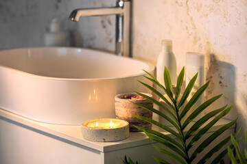 Holder with burning candle and sink on table in bathroom, closeup