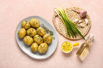 Plate of boiled baby potatoes with dill and green onion on pink background