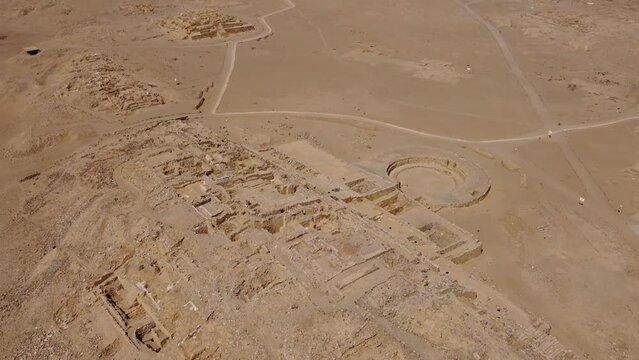 Aerial video of the ancient archaeological UNESCO site of Caral. Drone hovers above and camera slowly tilts up showing many stone pyramids. Located in the Supe valley of Lima, Peru.