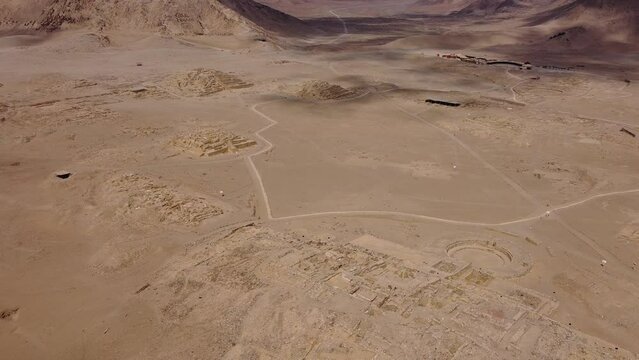 Cinematic aerial footage of archaeological UNESCO site of Caral. One of the oldest cities in the world. Drone orbits above the ancient pyramids and temples. Located in the Supe valley of Lima, Peru.