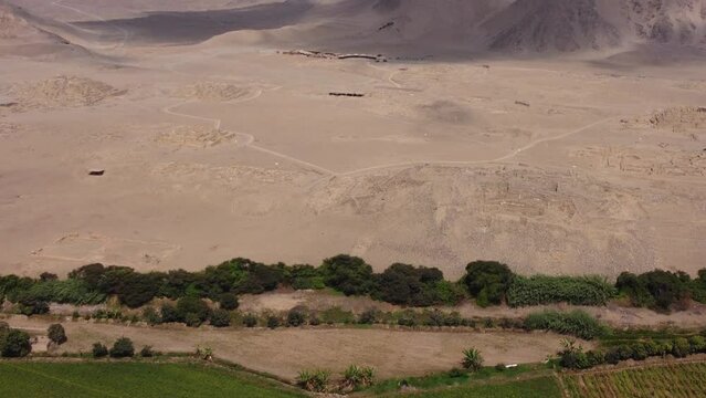 Aerial video archaeological site called Caral. The oldest city in the Americas and one of the oldest in the world. Drone hovers and slowly tilts camera up. Located in the Supe valley of Lima, Peru.