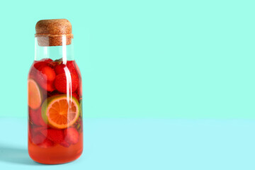 Bottle of infused water with strawberry and lime on blue background