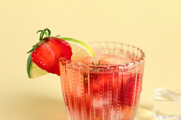 Glass of infused water with strawberry and lime on yellow background