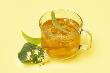 Glass cup of linden tea on yellow background