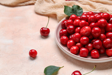 Plate with sweet cherries on pink background