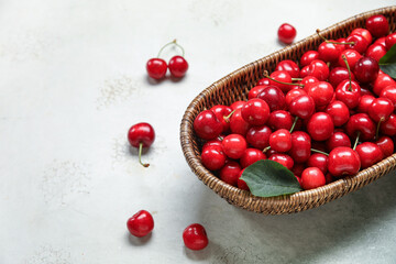 Wicker bowl with sweet cherries on white background