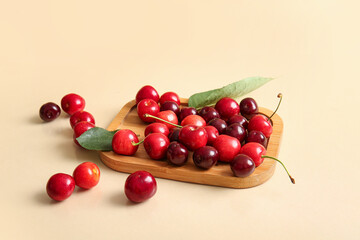 Board with sweet cherries on beige background
