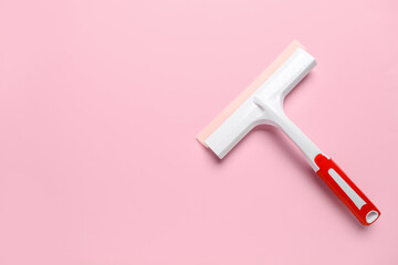 White plastic squeegee on pink background