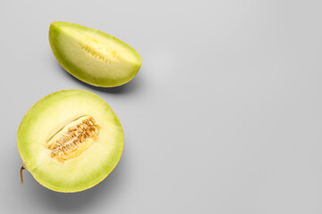 Half of sweet melon with piece on grey background
