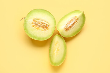 Half of sweet melon with pieces on yellow background