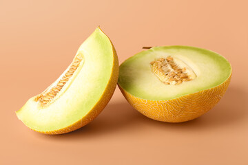 Half of sweet melon with piece on orange background
