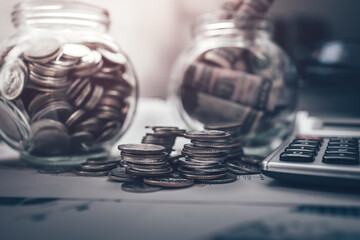 Stack of money coin for saving money growing business, saving plan. Calculator, pen, business graph in workplace. Business and finance concept.