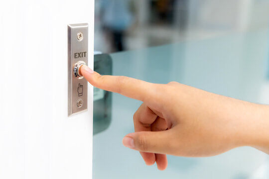 Closeup icon hand press on exit push button with finger point to digital door security in building. Safety door in office building for entrance-exit security system.