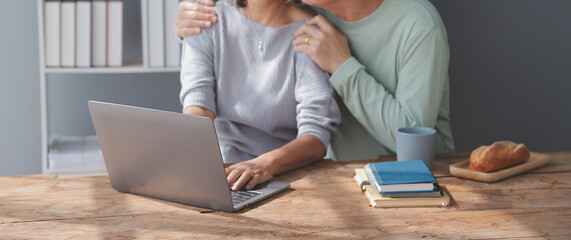 Embraced mature couple surfing the Internet on laptop at home