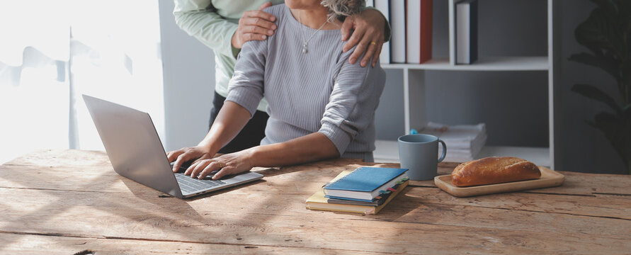 Embraced mature couple surfing the Internet on laptop at home