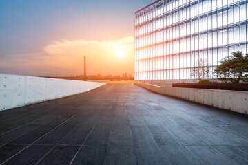Obraz premium Walkway and glass wall with city skyline at sunset