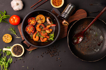 Grilled prawns served on a plate with lemon. Garlic on dark black background. Seafood. Top view.