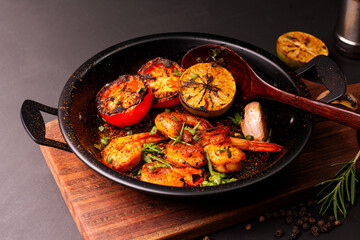 Grilled prawns served on a plate with lemon. Garlic on dark black background. Seafood. Top view.