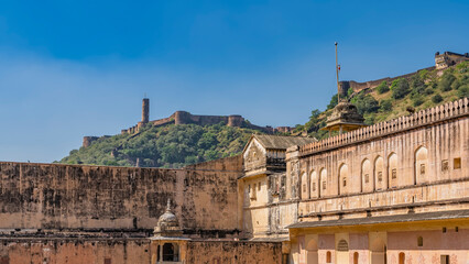 Obraz premium Weathered sandstone walls of the ancient Amber Fort. There is a protective fortress wall on the ridge of the mountain. Blue sky. Jaipur. India. 