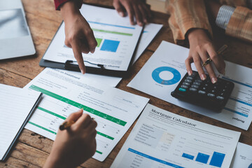 Businesswoman teamwork discussing brainstorming and calculating with calculator on evaluation data in conference room Focus on business growth and point out financial accounting charts.