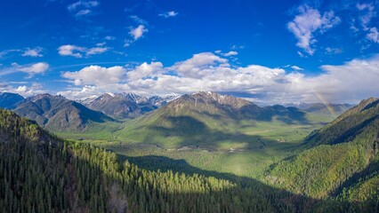 Aerial panorama of mountains in wild northern forest with rainbow and river