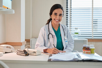 Portrait of beautiful female doctor and professional nutritionist in uniform smiling and looking at...