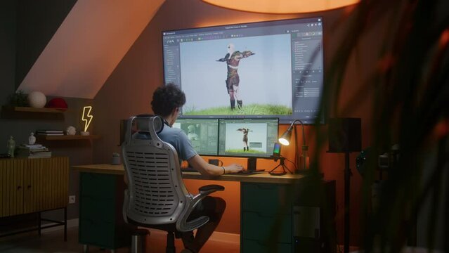 Young 3D designer creates animation for video game character, works remotely from home late night on computer and big digital screen with professional software interface for 3D modeling and design.